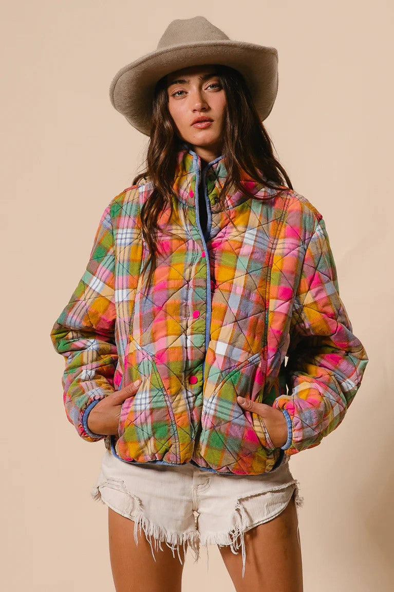 Person wearing a colorful plaid jacket and beige hat on a beige background