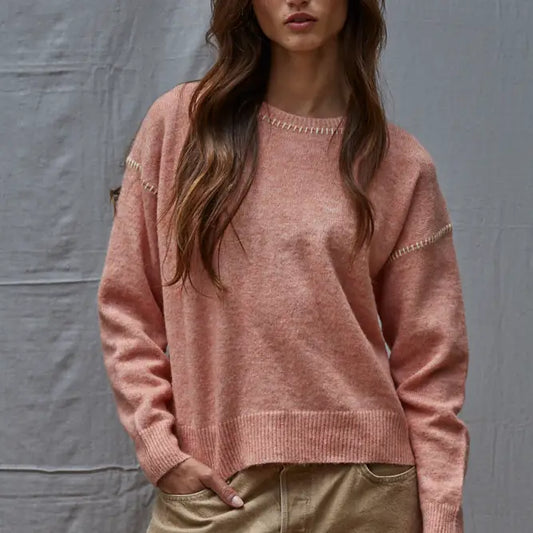 Person wearing a pink sweater against a gray background