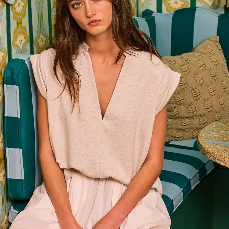Woman wearing cap sleeve v-neck shirt sitting on a green striped couch