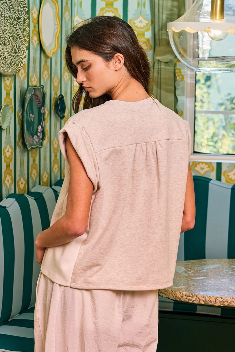Back view of woman wearing a beige tucked sleeve shirt and pants