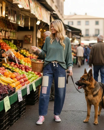 Woman walking a dog in an outdoor market with fruit and vegetable stands.