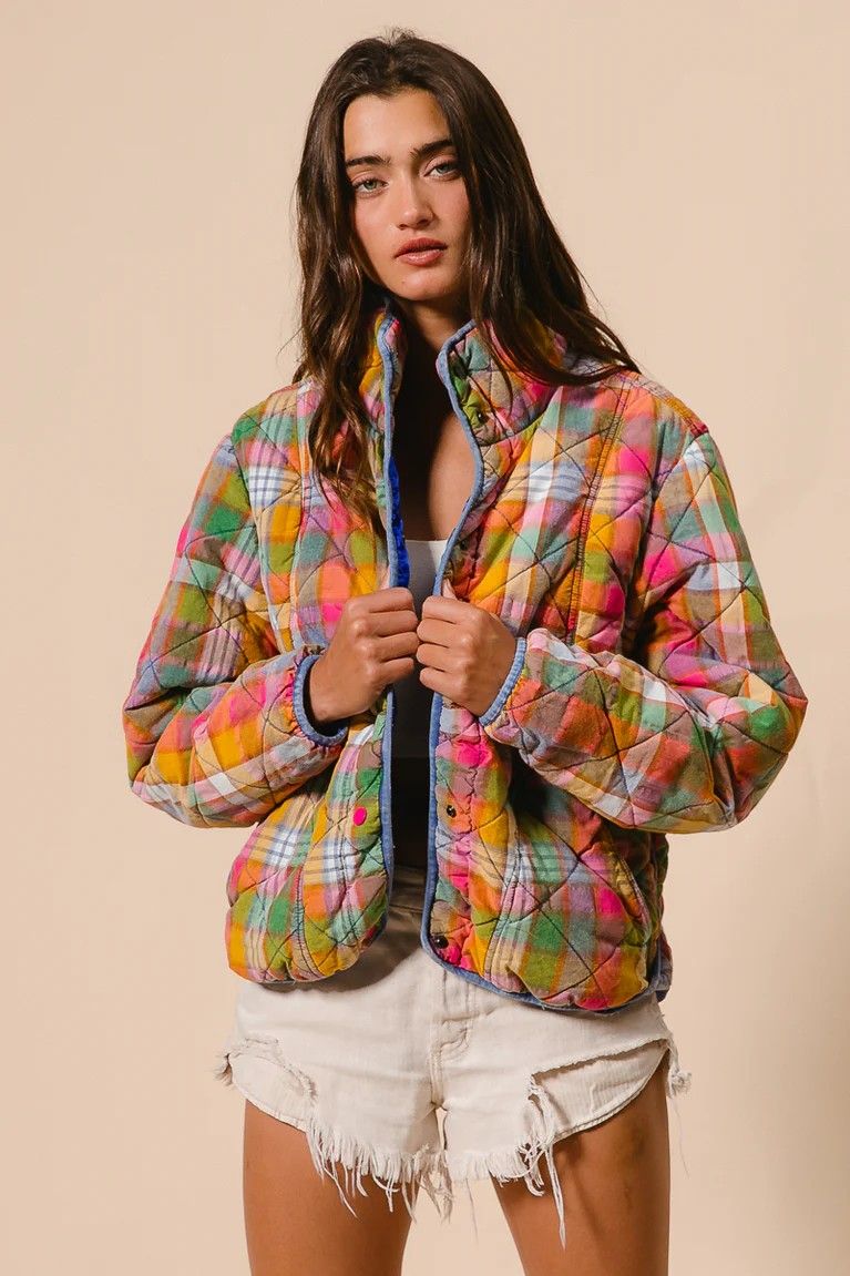 Woman wearing a colorful quilted jacket against a beige background